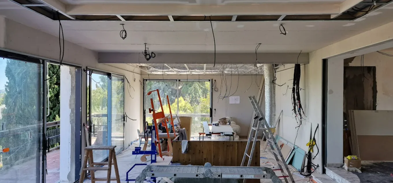 Séjour en travaux avec faux plafond en cours de pose et grande baie vitrée